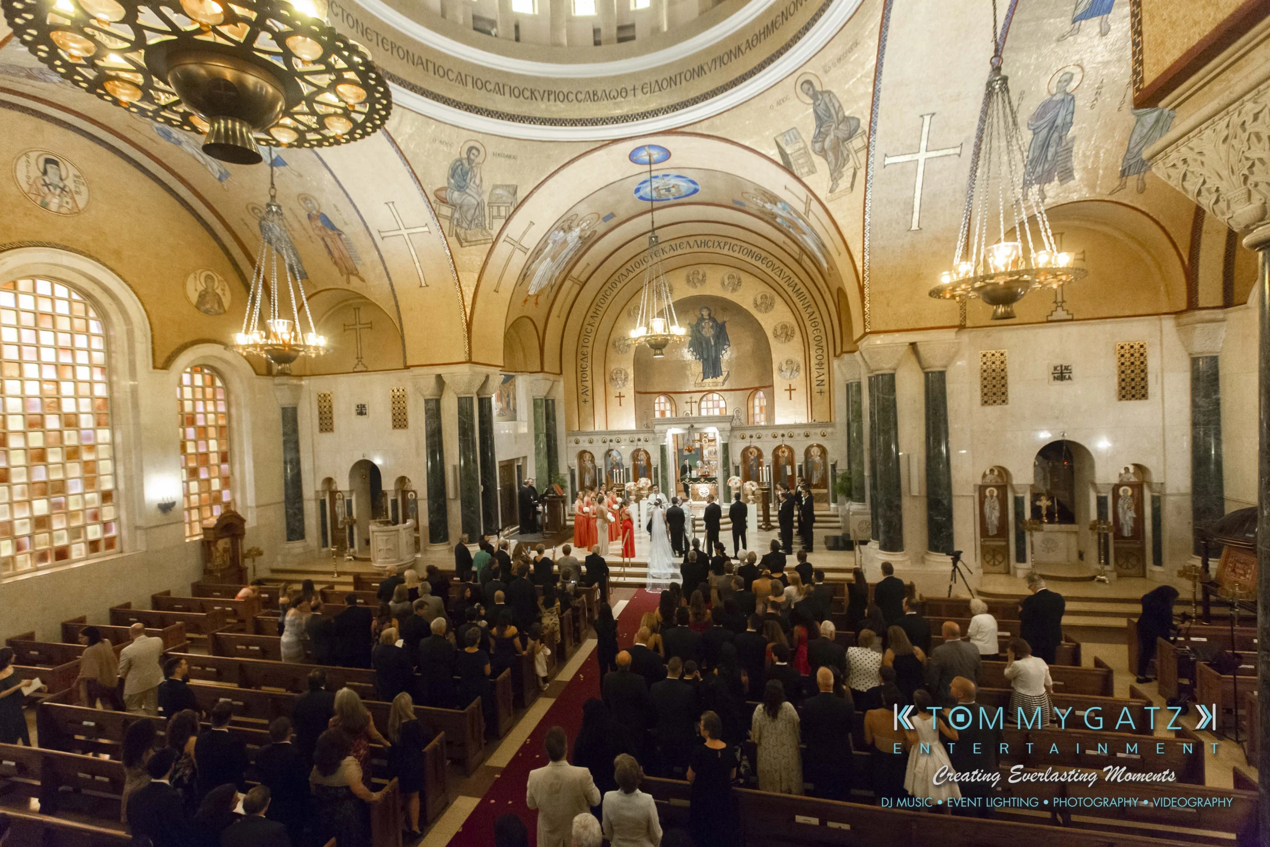 A large, ornate church interior hosts a wedding ceremony with a bride, groom, and guests seated in pews.