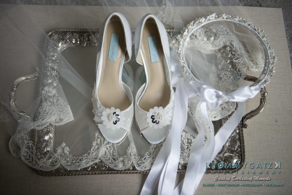 White bridal shoes and a floral headband with ribbons on a decorative tray with lace accents.