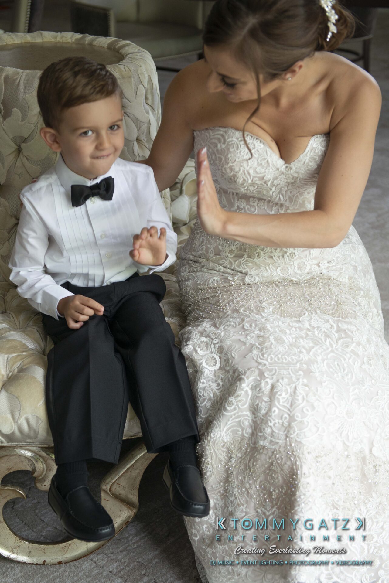 Urania-Aristidis-060218-PREP-Low-Res-WM-64 - TOMMY GATZ ENTERTAINMENT A bride playfully gestures while sitting with a young boy in formal attire.
