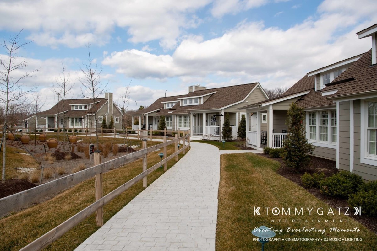 BrittanyDaniel-WEDDING-Highlights-19 - TOMMY GATZ ENTERTAINMENT Sidewalk between landscaped gardens and suburban houses under a partly cloudy sky.