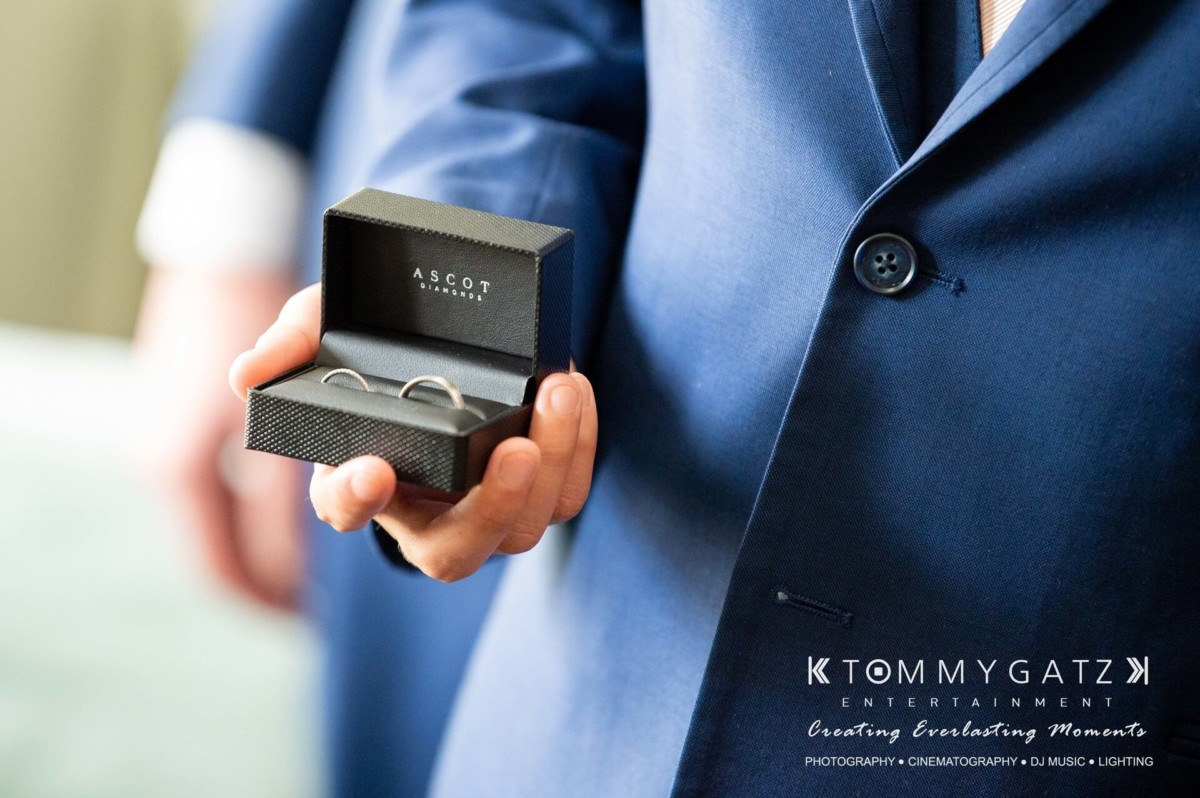 BrittanyDaniel-WEDDING-Highlights-21 - TOMMY GATZ ENTERTAINMENT A person in a blue suit holds a small black box containing two rings.