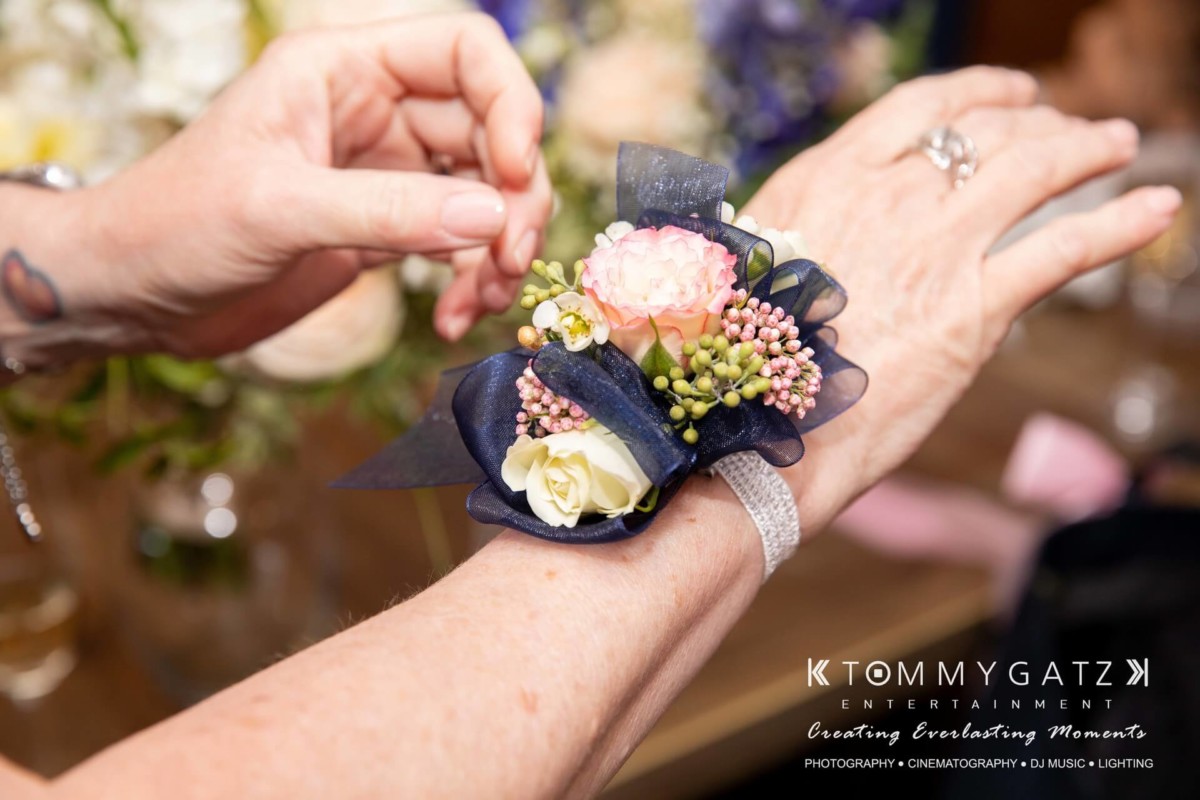 BrittanyDaniel-WEDDING-Highlights-49 - TOMMY GATZ ENTERTAINMENT A person wears a floral corsage with pink, white, and green flowers on their wrist.
