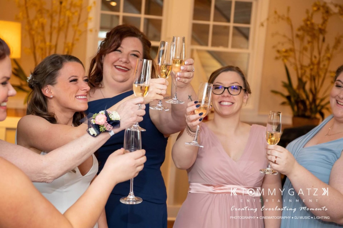 BrittanyDaniel-WEDDING-Highlights-52 - TOMMY GATZ ENTERTAINMENT A group of people in formal attire raising glasses in a toast, smiling.
