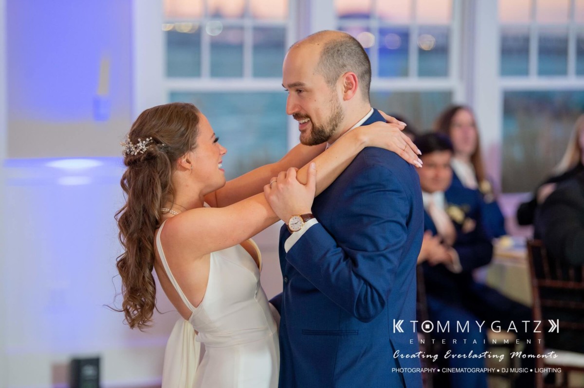 BrittanyDaniel-WEDDING-Highlights-96 - TOMMY GATZ ENTERTAINMENT A bride and groom share their first dance at a wedding reception, with guests seated in the background.