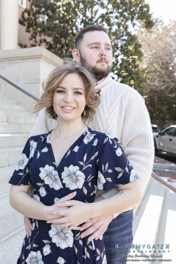 Shannon-James-031319-FINALS-Low-Res-WM-10 - TOMMY GATZ ENTERTAINMENT A couple poses on outdoor steps. The woman is in a floral dress, and the man is in a light sweater. Both are smiling.