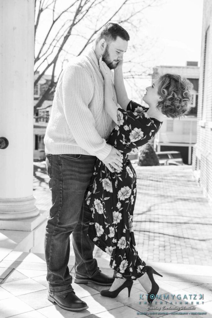 Shannon-James-031319-FINALS-Low-Res-WM-12 - TOMMY GATZ ENTERTAINMENT A couple embraces on a porch, with the woman reaching up to touch the man's face. The setting is outdoors on a sunny day.