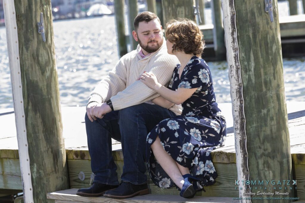Shannon-James-031319-FINALS-Low-Res-WM-19 - TOMMY GATZ ENTERTAINMENT A couple sits on a wooden dock by the water, with the woman in a floral dress and the man in a sweater and jeans.