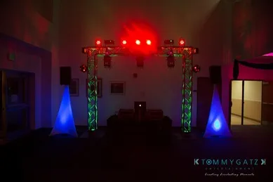 A DJ booth with colorful lights and speakers set up in a dimly lit room.