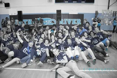 A group of people wearing sports jerseys pose for a photo in a gymnasium.