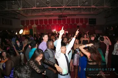 People dancing energetically at a crowded indoor party with colorful lights and decorations.