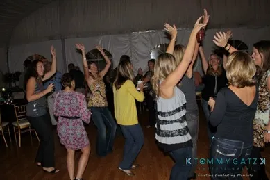 A group of women dancing and socializing at a gathering in a dimly lit room.