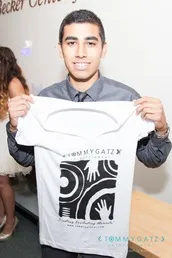 Person holding a white T-shirt with black and white design, smiling at the camera.