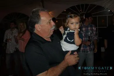 A man holding a child at a dimly lit indoor event.