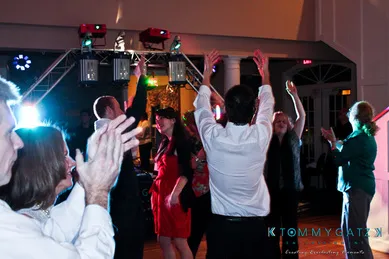 People dancing energetically under colorful lights in a party setting indoors.