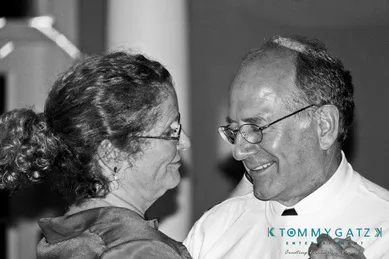 A black and white image of an older man and woman smiling at each other while dancing.