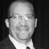 Black and white photo of a smiling man wearing glasses and a suit.