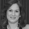 Black and white photo of a woman smiling, with shoulder-length hair, wearing a necklace and earrings.