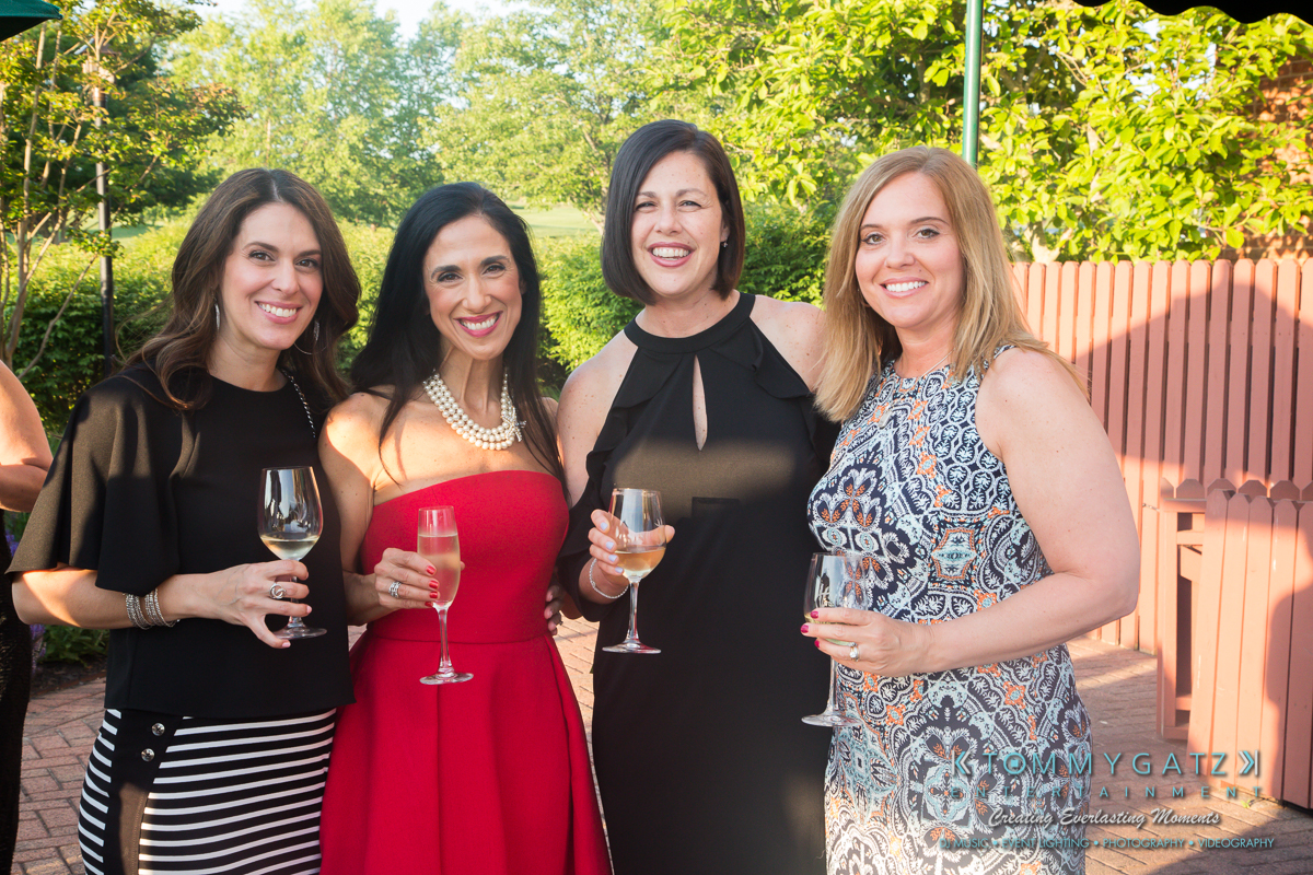 Garbis-Grad-Edits-lowres-Watermark-103 - TOMMY GATZ ENTERTAINMENT Four women in formal attire stand outside, holding wine glasses and smiling.