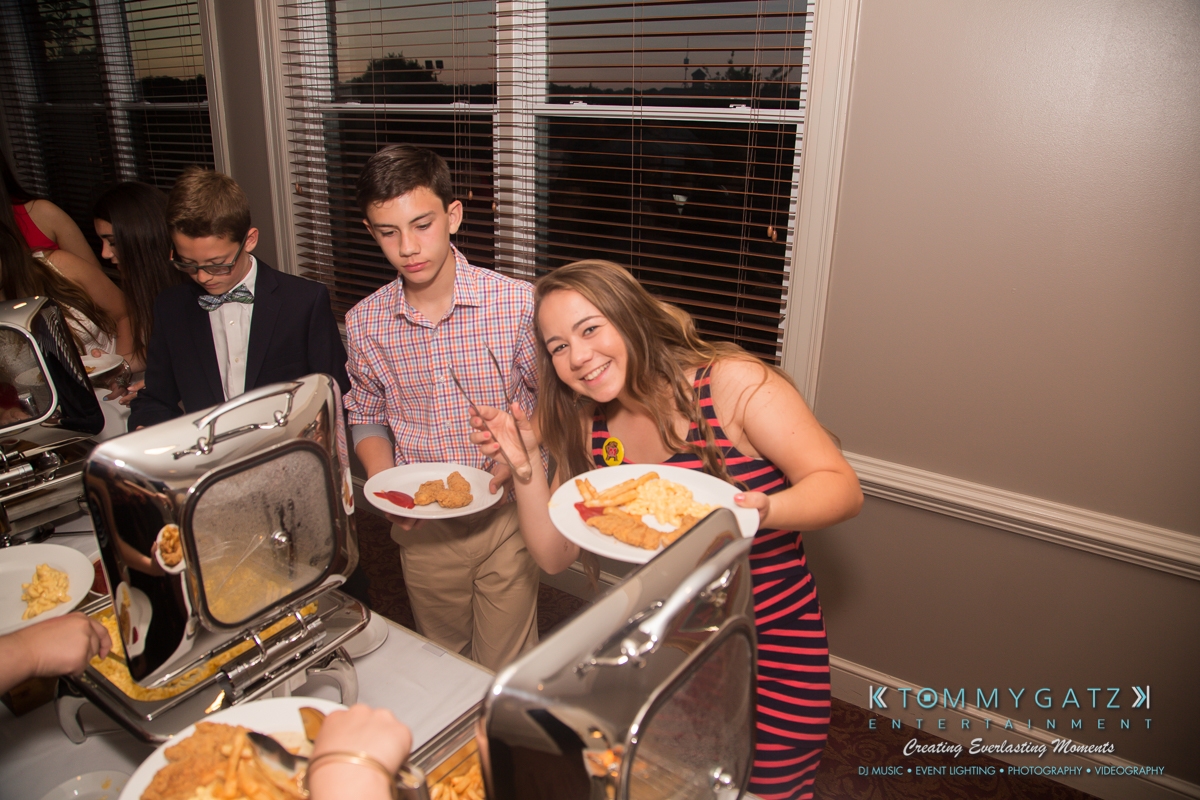 Garbis-Grad-Edits-lowres-Watermark-178 - TOMMY GATZ ENTERTAINMENT People serving themselves food from a buffet at an event, holding plates with fried items and condiments.