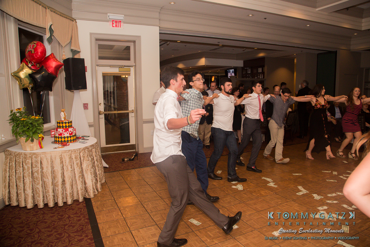 Garbis-Grad-Edits-lowres-Watermark-274 - TOMMY GATZ ENTERTAINMENT Group of people dancing indoors on a wooden floor, with a decorated table and balloons in the background.
