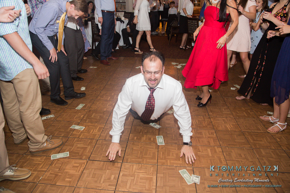 Garbis-Grad-Edits-lowres-Watermark-360 - TOMMY GATZ ENTERTAINMENT A man in a white shirt crawls on a dance floor surrounded by people and scattered dollar bills.