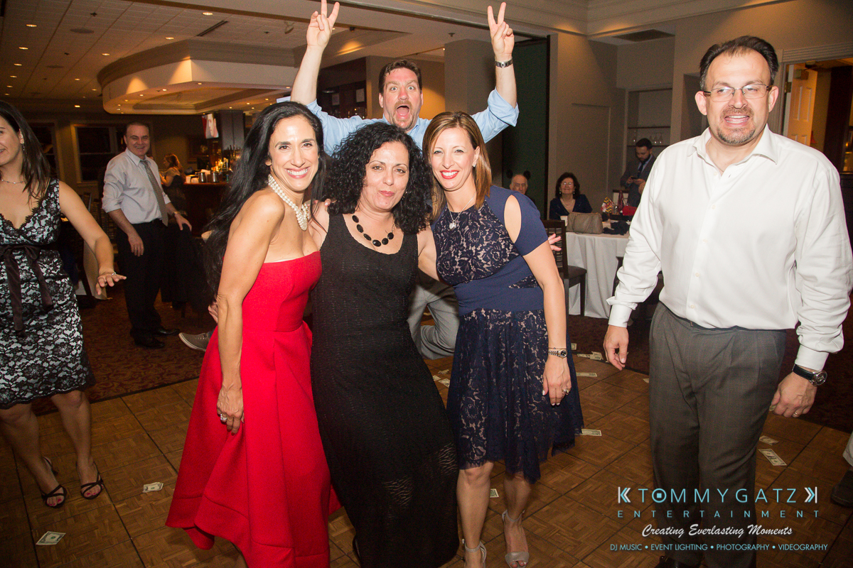 Garbis-Grad-Edits-lowres-Watermark-469 - TOMMY GATZ ENTERTAINMENT A group of people smiling and posing on a dance floor at an event, with one person playfully making peace signs in the background.