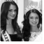 Two women wearing tiaras and sashes, smiling at the camera.