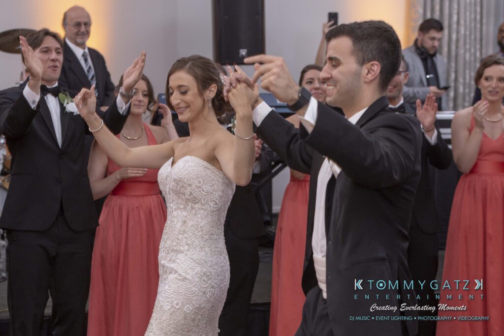 Bride and groom dance joyfully surrounded by bridesmaids and groomsmen at a wedding reception.