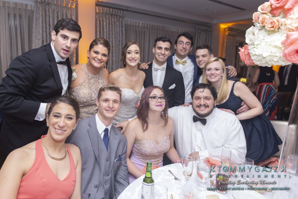 Group of people dressed in formal attire posing together at a table during an indoor event.