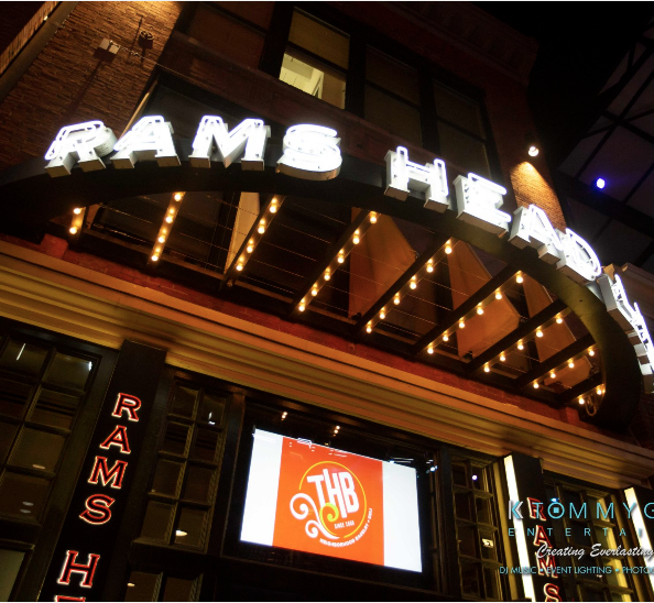 Neon-lit entrance of Rams Head Live music venue with digital screen displaying a logo.
