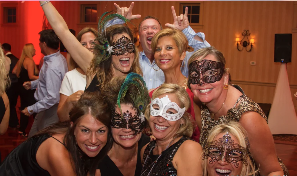 People in a group photo at a party, some wearing decorative masks.